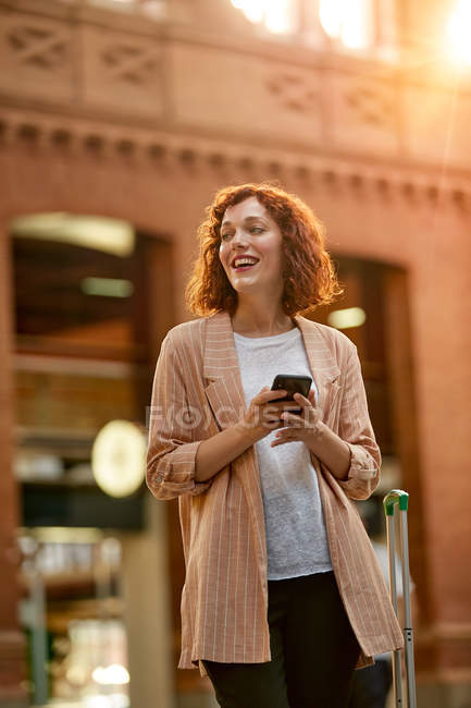 Червоне волосся молода жінка використовує смартфон на станції — стокове фото
