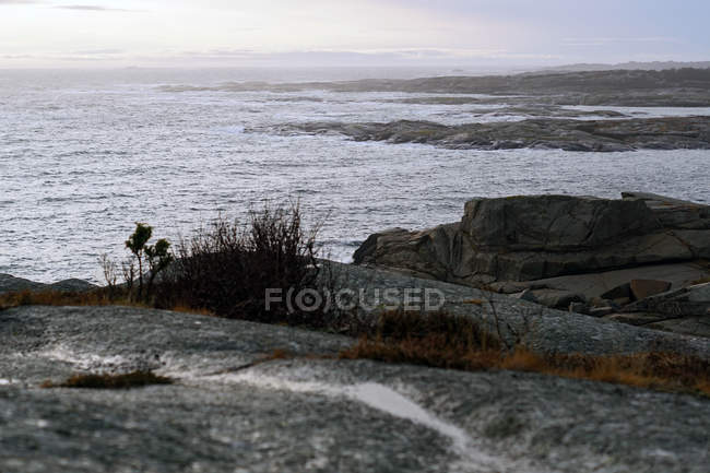 Smooth boulders on empty coast with sea waves under dark evening sky in Norway — Stock Photo