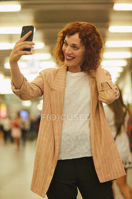 Rothaarige junge Frau nutzt Smartphone am Bahnhof — Stockfoto