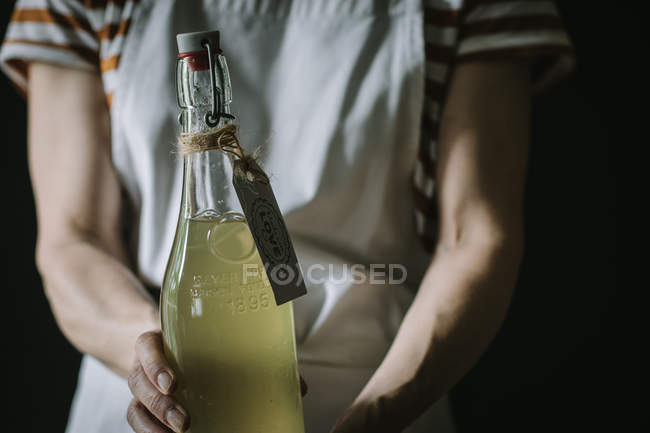 Close-up of woman holding bottle of elderflower drink with Made with love label — Stock Photo