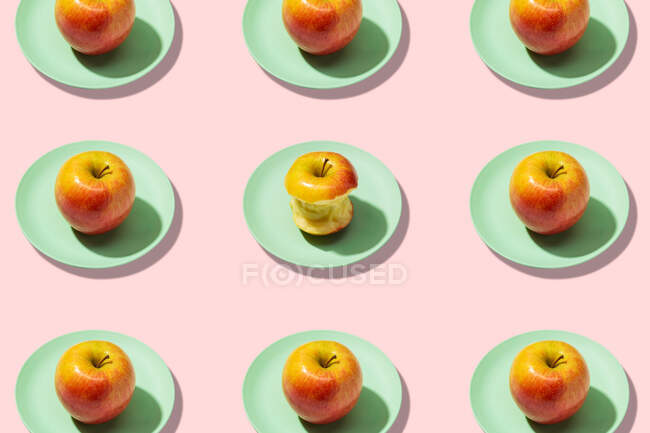 Maçãs frescas e maçã mordida em prato no fundo rosa. Padrão colorido vibrante — Fotografia de Stock