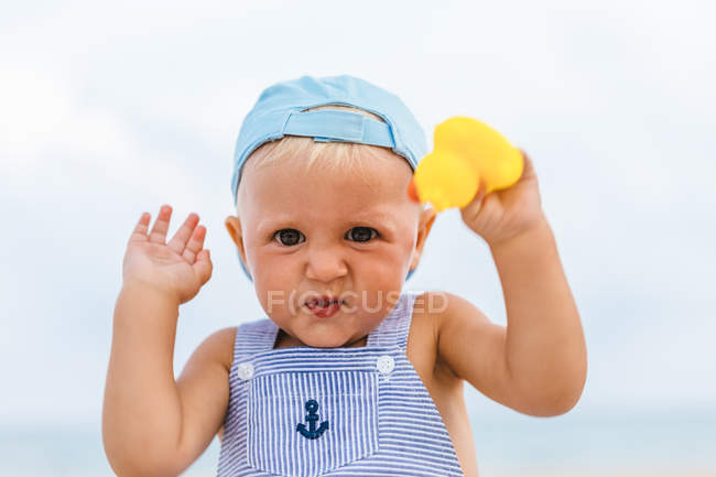 Портрет мальчика, играющего с резиновыми утками на пляже — стоковое фото