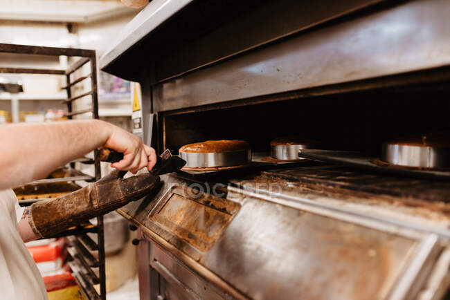 Чоловік заглядає всередину професійної печі під час роботи в пекарні — стокове фото