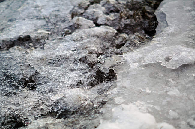 Melting ice and snow on top of rocky surface with pebbles in daylight — Stock Photo