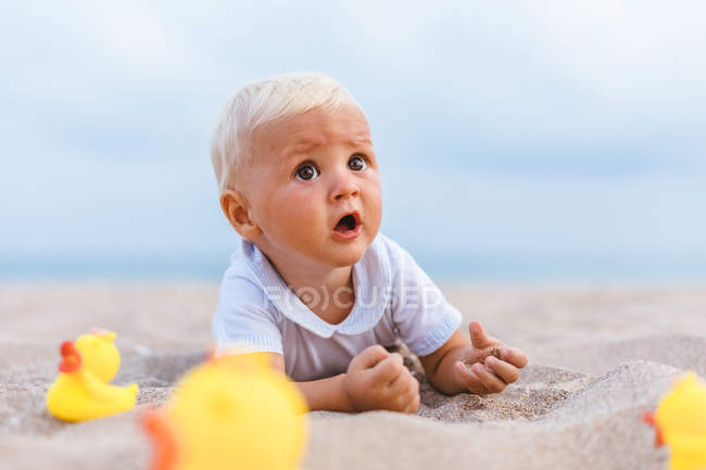 Портрет хлопчика, який грає з гумовими качками на пляжі — стокове фото