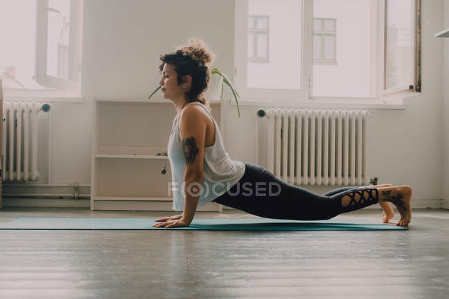 Side view of flexible woman in activewear exercising and standing on hands on floor in apartment — Stock Photo