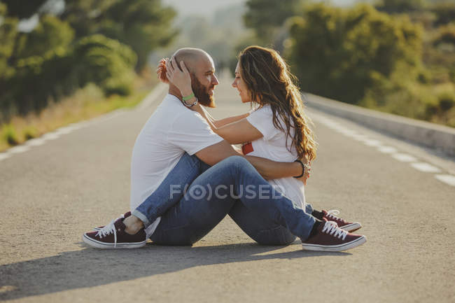 Casal afetuoso abraçando sessão próxima na estrada rural — Fotografia de Stock