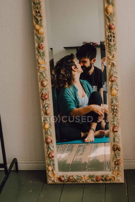 Reflection of tender kissing couple in tall decorated mirror — Stock Photo