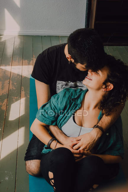 Affectionate couple in casual outfits kissing and embracing while resting in modern apartment — Stock Photo