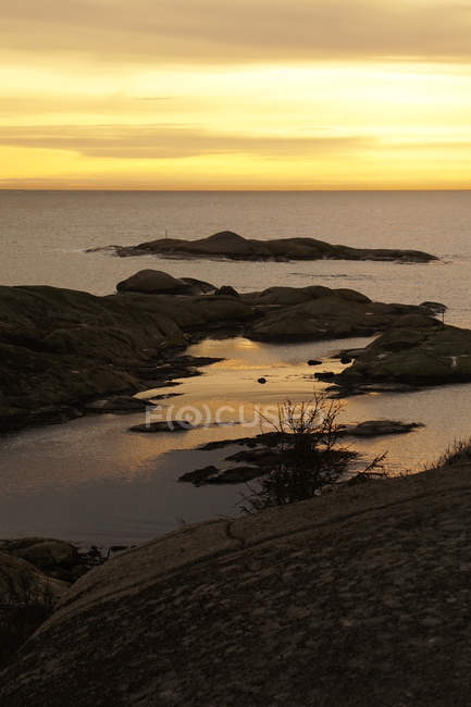 Rough formation of huge rocky cliffs above peaceful frozen coast against scenic evening sky — Stock Photo