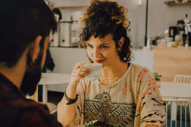 Ласковая пара в повседневной одежде сидит за столом в кафе и смотрит друг на друга — стоковое фото