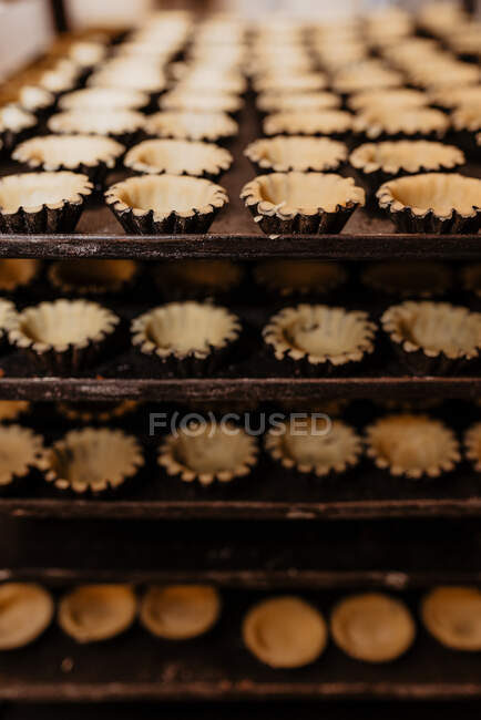 Set of empty raw pastry cases placed on metal trays in bakery — Stock Photo