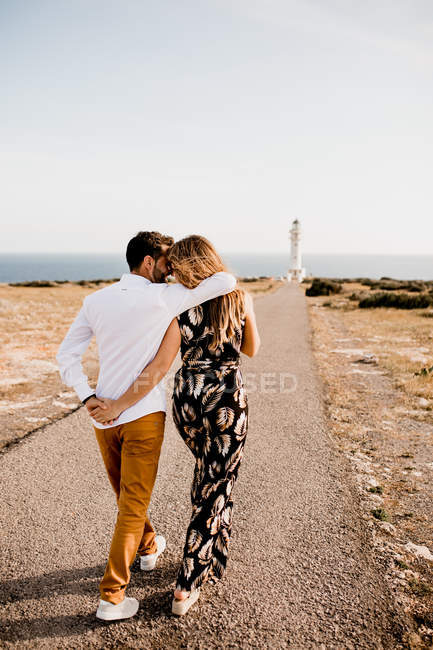 Smiling lovers cuddling on path to sea — Stock Photo