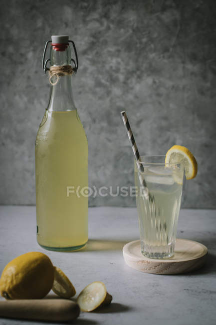 Délicieux sirop de fleurs de sureau en verre et bouteille sur table avec coupée en tranches citron — Photo de stock