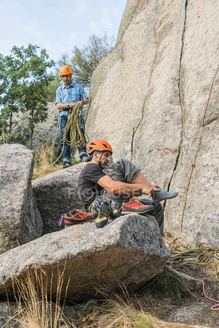 Ein Bergsteiger zieht seine Kletterschuhe an, um mit dem Klettern zu beginnen — Stockfoto