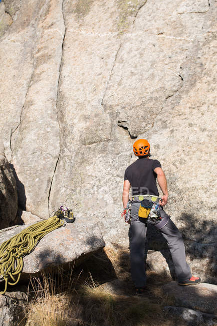 Rock climber with orange helmet is staring at the top of the mountain he is going to climb — Stock Photo