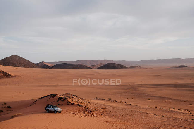 Транспортні засоби посеред пустинної дороги на сірий день з викривленим килимом у Марокко. — стокове фото