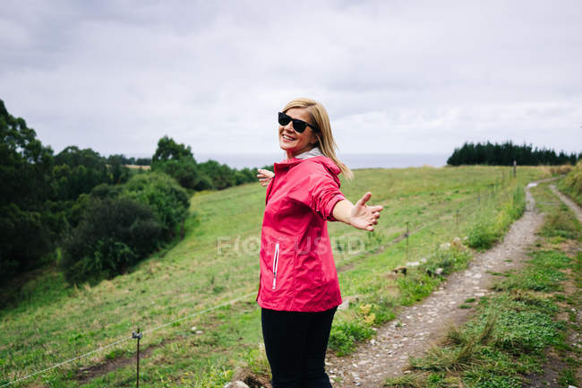 Pleasant relaxed woman in red jacket looking at camera and stretching hands — Stock Photo