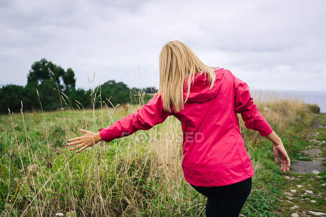 Cheerful woman enjoying countryside landscape and stretching hands — Stock Photo