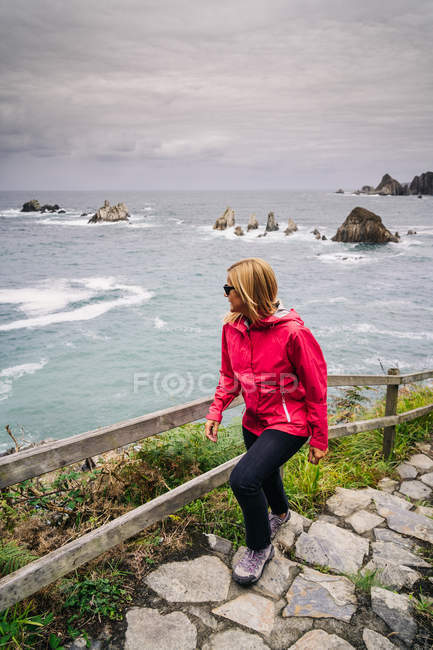 Mujer subiendo escaleras que vienen de la orilla del mar - foto de stock
