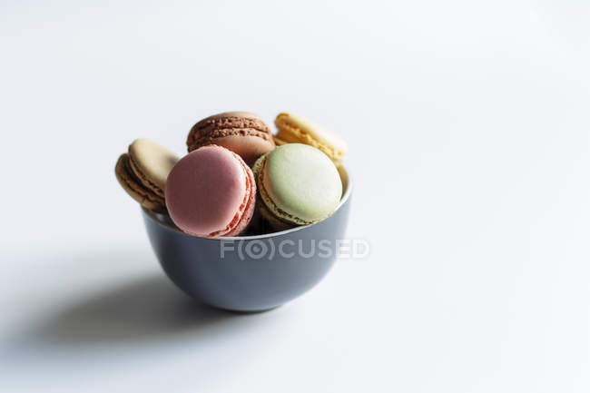 Ciotola di macaron freschi colorati su sfondo bianco — Foto stock