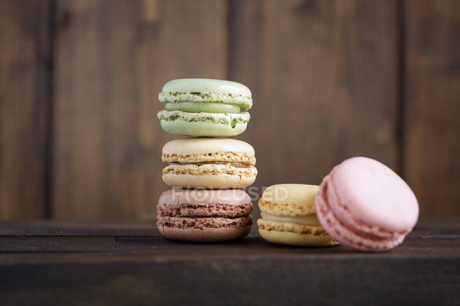 Colorful tasty macaroons stacked in pile against brown lumber wall — Stock Photo
