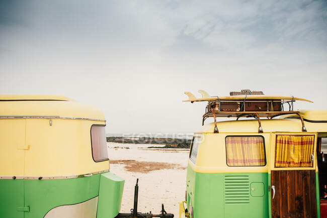 Minibus colorido com reboque estacionado na costa arenosa em dia ensolarado — Fotografia de Stock