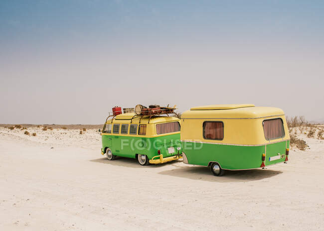 Красочный микроавтобус с прицепом, припаркованным на песчаном берегу в солнечный день — стоковое фото