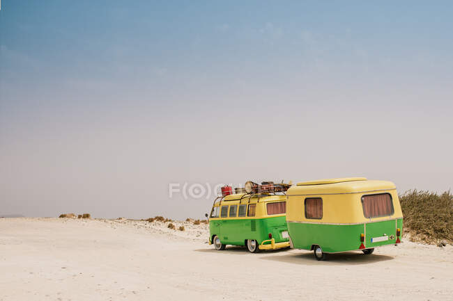 Colorful minibus with trailer parked on sandy shore in sunny day — Stock Photo