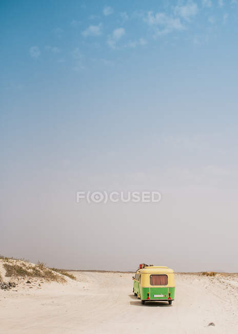 Minibus colorato con rimorchio parcheggiato sulla riva sabbiosa nella giornata di sole — Foto stock
