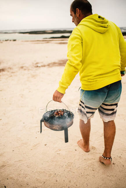 Tanned man cooking on camping stove beside parked mini van — Stock Photo
