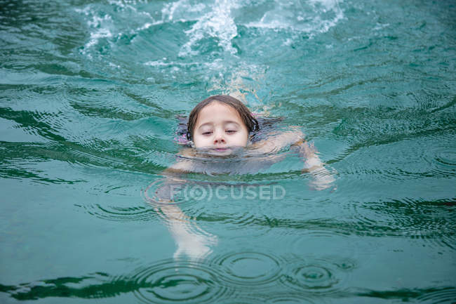 Little girl swimming in clean warm water of pond in spa and enjoying weather — Stock Photo