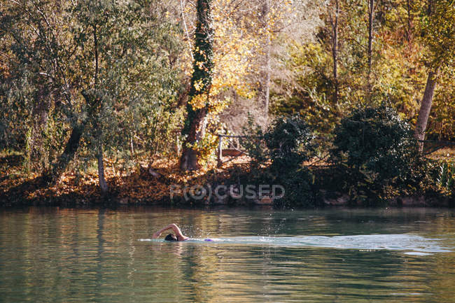 Далекая женщина плавает в чистой теплой воде пруда в спа и наслаждается солнечным днем — стоковое фото
