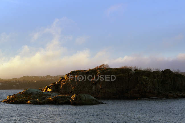 Tranquil mar con rocas de roca en el lago en rayos solares. - foto de stock