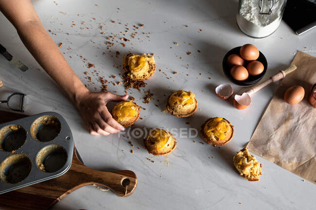 From above crop person hand holding a homemade cupcakes on wooden table with arranged eggs — Stock Photo