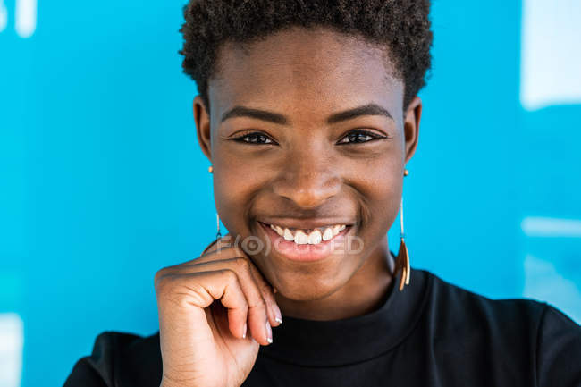 Porträt einer intelligenten afrikanisch-amerikanischen Frau, die vor blauem Hintergrund in die Kamera blickt — Stockfoto
