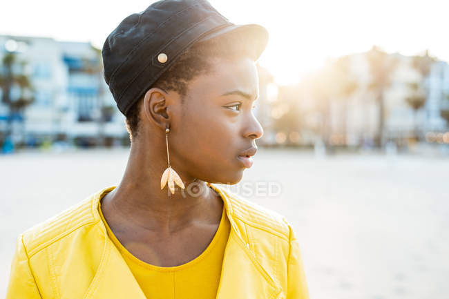 Портрет афро-американської жінки в стильному яскравий жакет дивлячись на піщаний пляж розмитий фон — стокове фото