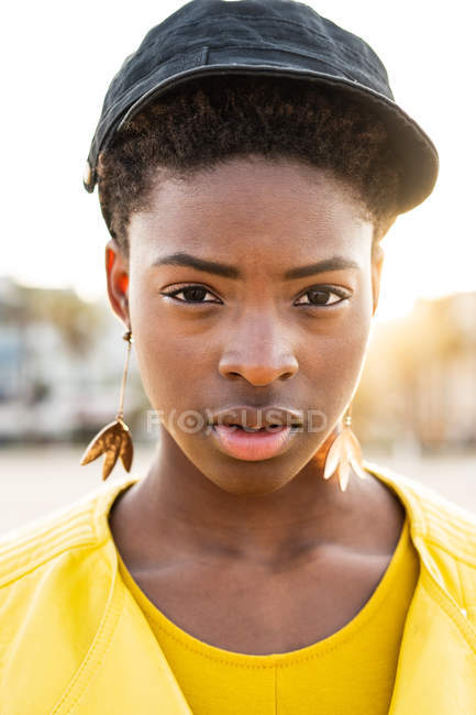 Porträt einer afrikanisch-amerikanischen Frau in stylischer heller Jacke, die in die Kamera am Sandstrand blickt — Stockfoto
