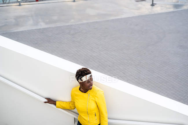 Blick aus der Vogelperspektive auf eine fröhliche Afroamerikanerin in stylischer Kleidung, die auf Treppen chillt und wegschaut — Stockfoto
