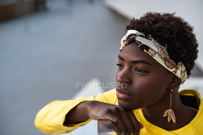 Hohe Winkel der frohen afrikanisch-amerikanischen Frau in stylischer Kleidung chillt auf Treppen, lehnt am Geländer und schaut weg — Stockfoto