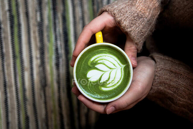 Von oben hält eine Person eine Tasse grünen Kaffee in der Hand — Stockfoto