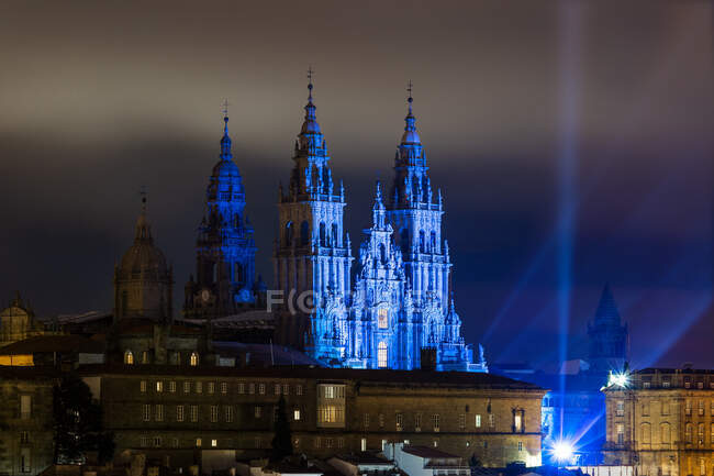 Türme der Kathedrale von Santiago de Compostela mit blauem Licht, nachts von Gebäuden umgeben — Stockfoto