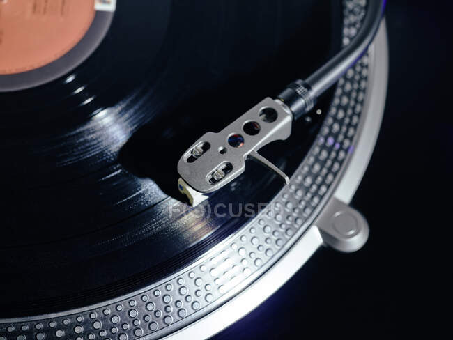 Nahaufnahme der Oberseite eines alten schwarzen Plattenspielers mit Tonarm, der die Position der Kassettenabtastrinne beibehält und Schallplatte abspielt — Stockfoto