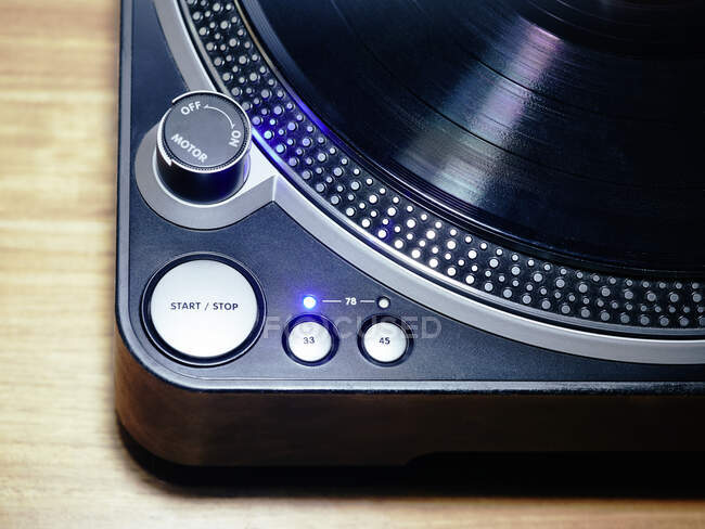 From above closeup of blue portable turntable with phonograph record set of controls and indicator light glowing behind 33 rpm button — Stock Photo