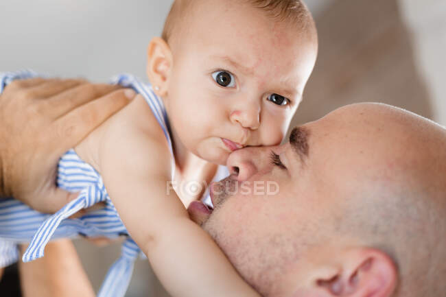 Взрослый мужчина целует очаровательного ребенка в щеку, проводя время вместе — стоковое фото