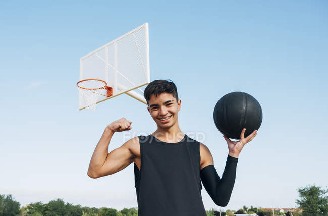 Junger Mann posiert mit Ball auf Basketballfeld. — Stockfoto