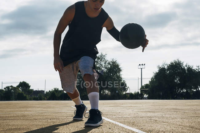 Jovem jogando na quadra de basquete ao ar livre . — Fotografia de Stock