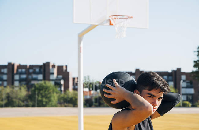 Молодий чоловік позує з м'ячем на баскетбольному майданчику на відкритому повітрі . — стокове фото