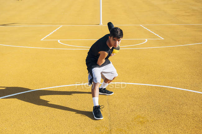 Молодий чоловік позує з м'ячем на баскетбольному майданчику на відкритому повітрі . — стокове фото