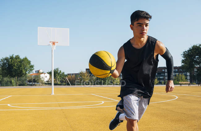 Молодой человек играет на баскетбольной площадке на открытом воздухе . — стоковое фото